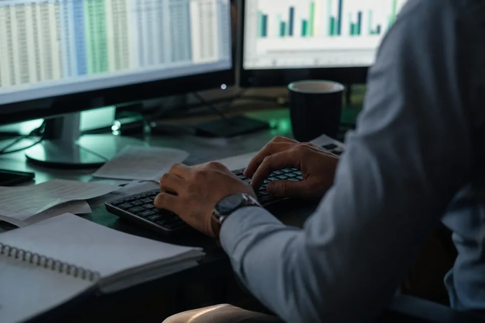 Analityk porównuje wyniki spółek w arkuszu na dwóch monitorach